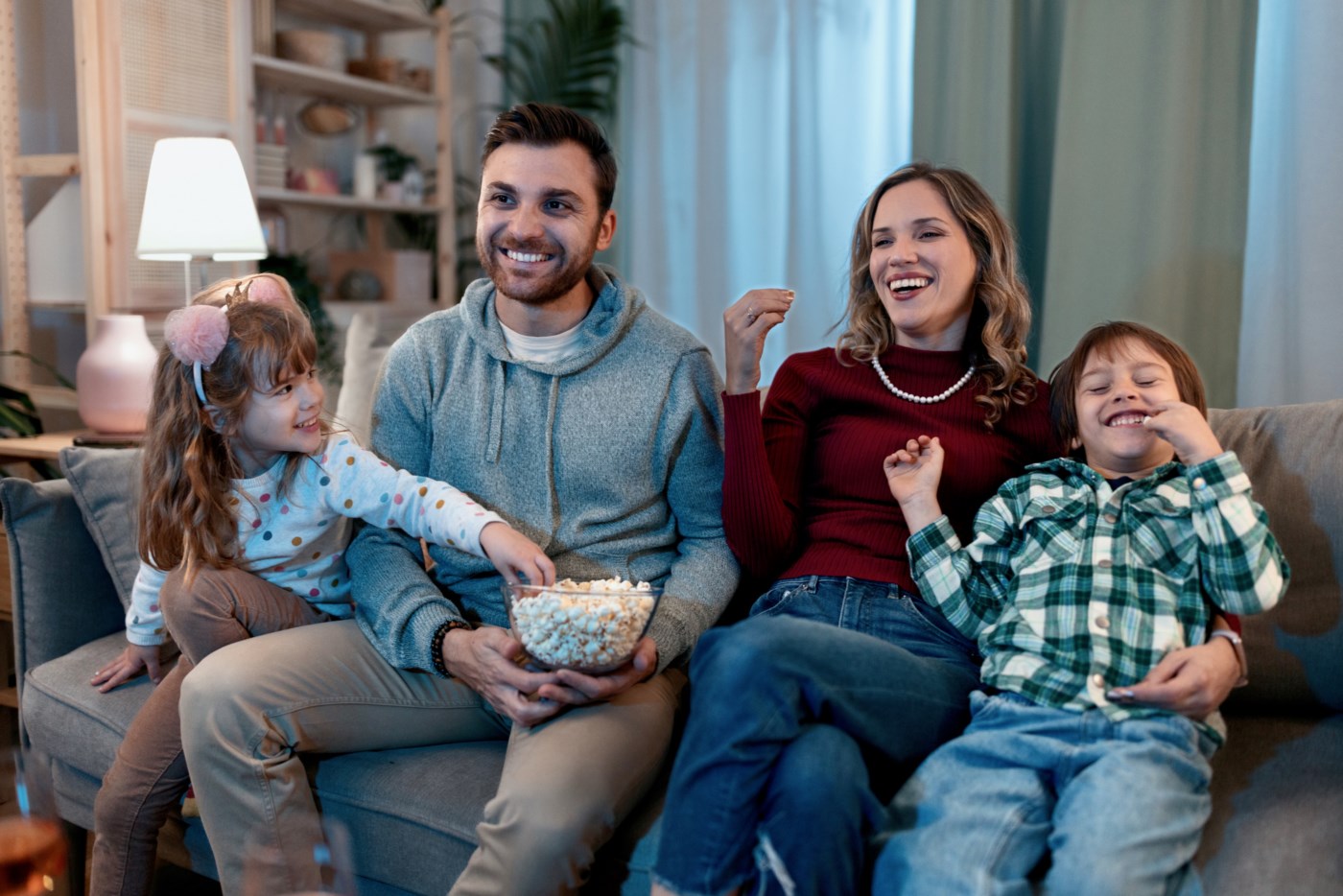 Glad familie på fire deler popcorn og ser på film i ein koseleg stove.