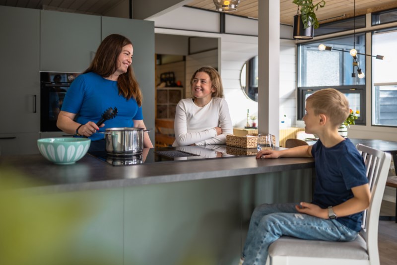 Kvinne og to barn lagar middag