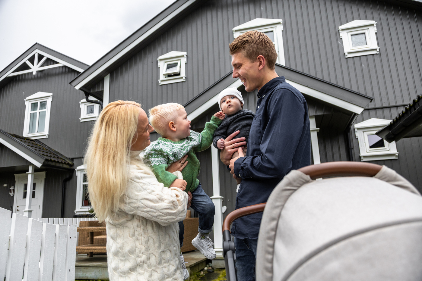 Mor, far og to barn står utanfor eit hus